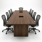Head-on view of the walnut conference table with two recessed power grommets, a two-section top and dark gray mesh task chairs