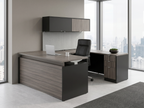 Gray woodgrain and charcoal sit-stand desk at seated height in a high-rise office with a black leather chair