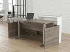 Gray reception desk with a floating glass counter in a white-brick coworking lobby