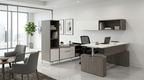 U desk with hutch in a corner office with city windows, guest chairs and a laptop