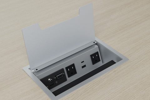 Silver power grommet with 2 outlets, USB charging and a connection plate, lid open in a light wood laminate top