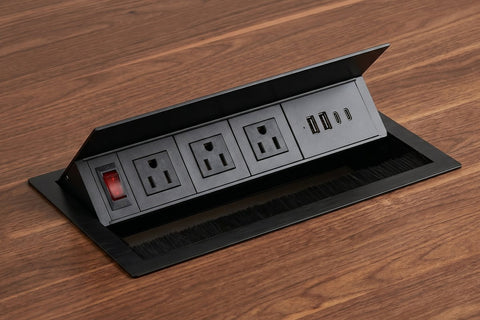 Black power grommet with 3 outlets, USB-A and USB-C ports and a switch, lid open in a walnut laminate top